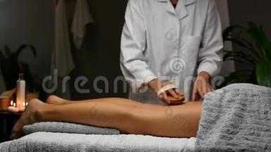 美丽的年轻女子在水疗中心接受抗纤维素按摩，按摩师做专业的腿部按摩