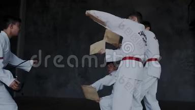 高思想，骄傲的年轻跆拳道战士跳和碰撞木板。 显示力量和战斗武术