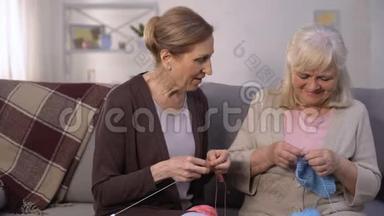 老年妇女学习与她成熟和有经验的朋友编织，爱好