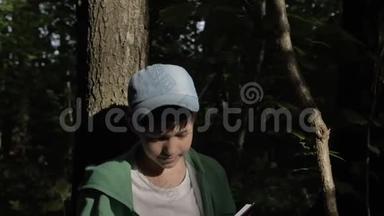 男孩坐在树<strong>下</strong>，在户外看一本有图表的书