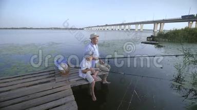 快乐的家庭，父亲和他戴着草帽的小男孩在<strong>河边</strong>的码头上<strong>钓鱼</strong>，玩得很开心