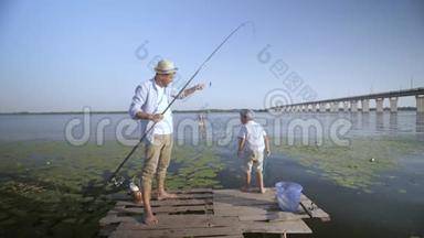 家庭活动，快乐的父亲拿着鱼竿，快乐的儿子在<strong>夏季周</strong>末在码头上快乐地钓鱼