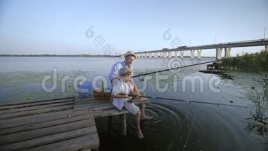 家庭周末在户外，父亲和儿子在暑假期间在芦苇丛中水边的木桥上钓鱼
