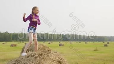 快乐的<strong>女孩</strong>在收获场的干草堆上跳舞。 在<strong>乡下</strong>的干草堆上跳舞的快乐<strong>女孩</strong>。 青年