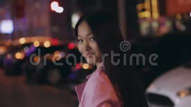 时髦的亚洲女人走在一个夜晚的城市里转脸，<strong>回头</strong>看
