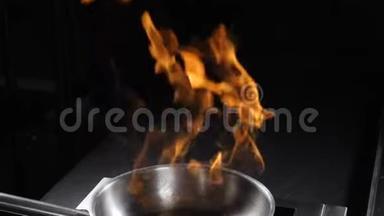 在黑暗的背景下，从不锈钢煎锅中升起<strong>火焰</strong>。 煮<strong>火焰</strong>菜。 厨师准备<strong>火焰</strong>杯的特写