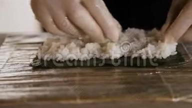 寿司师傅的特写镜头将米饭撒在诺丽身上。寿司制作过程。厨师的手