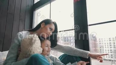 妈妈和儿子坐在窗台上，<strong>望</strong>着<strong>窗外</strong>