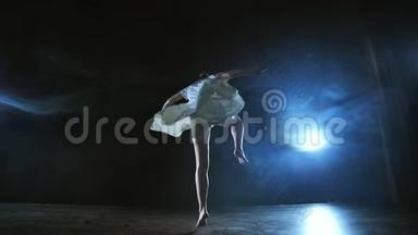 优雅的芭蕾舞演员在演播室里赤脚和白色宽松的<strong>超大礼</strong>服跳跃和跳舞。 带着烟。