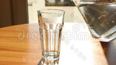 水从玻璃壶中倒入透明的玻璃杯