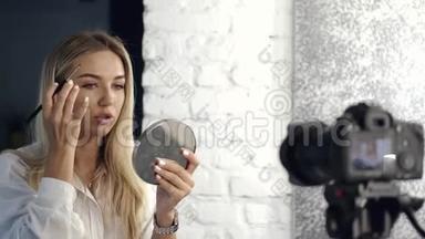 美女vlogger正在用镜子把她的眉毛画在照相机上