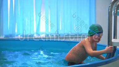 一个男孩在游泳池里，带着泳镜上楼梯，走出游泳池。