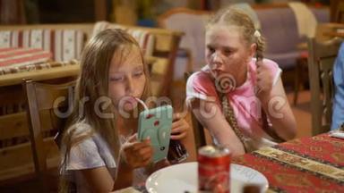 十几岁的女孩<strong>看</strong>着智能<strong>手机</strong>在吃饭。 年轻女孩用<strong>手机看</strong>视频。 两个女朋友