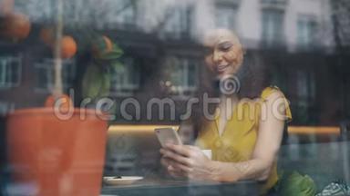 在咖啡馆里，一个微笑的年轻女子在看智能<strong>手机屏</strong>幕