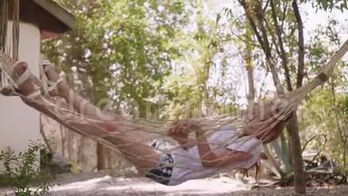 放轻松的女孩在暑假在吊床上摇摆。 少女在树上的夏日花园的吊床上放松