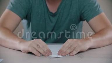 男人在桌子上折叠一架纸飞机