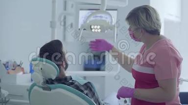 戴口罩和手套的牙医在现代牙科诊所使用医疗工具检查病人的口腔