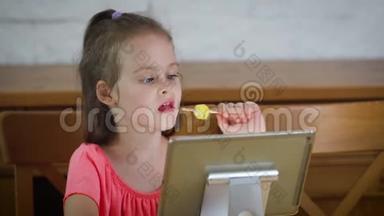 美丽的小女孩吃冰淇淋，看<strong>平板</strong>电脑上的<strong>卡通</strong>