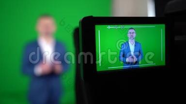 一个博主正在绿色背景上录制视频.. 摄像机正在记录一个博主