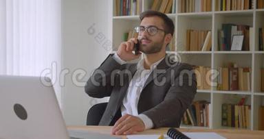 戴着眼镜、坐在笔记本电脑前打电话的成年白种人商人的特写照片