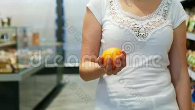 在超市里，女人的手慢慢地举起五颜六色的橘子