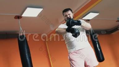 一个胖汗的家伙训练后累了，在健身房脱下拳击手套。 丰满男子个人减肥训练