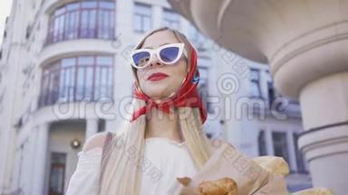站在街上拿着刚烤好的面包和羊角面包的时尚年轻女人的肖像。 时尚迷人