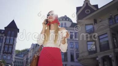 时尚漂亮的年轻<strong>女人</strong>，带着一杯咖啡站在街上<strong>晒太阳</strong>，用手机说话。 吸引力