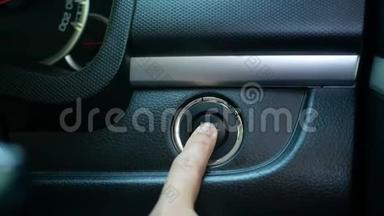 司机的特写`按下按钮启动汽车中的发动机。 技术和运输理念..