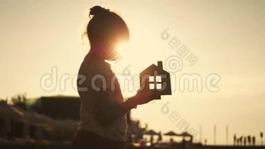 日落时，女孩在海滩上拿着纸房子。 人，<strong>梦想</strong>，家庭，房地产和家居理念.. <strong>儿童</strong>梦