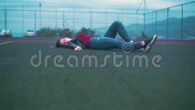 一个美丽而热情的女孩躺在法庭的地板上。 一个年轻的女人躺在球场的绿色表面上。