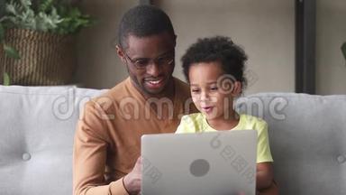 快乐的黑人父亲教孩子用笔记本电脑阅读