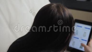女孩用数字平板电脑制作<strong>网上销售</strong>购物概念。 黑发女人躺在沙发上看生活方式在线商店