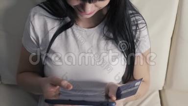女孩用笔记本电脑数字平板电脑制作网上销售购物概念。 黑发女人躺在沙发上看着商店的生活方式