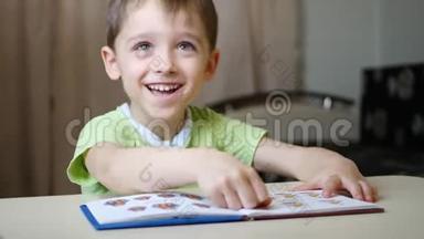 一个快乐的孩子微笑着看书，一边看着照片一边坐在家里的桌子旁