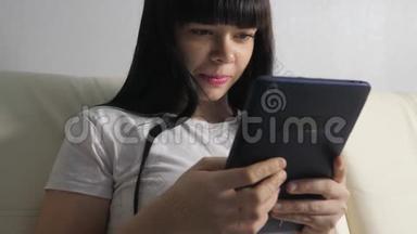 女孩用笔记本电脑数字平板电脑制作网上销售购物概念。 黑发女人躺在沙发上看生活方式店
