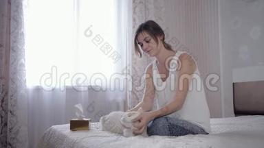 过敏症状，年轻女子坐在床上玩猫<strong>戏水</strong>，由于头发的缘故，经常用手帕打喷嚏