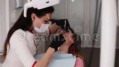 <strong>牙医</strong>办公室，一位穿着白色长袍和面具的年轻女<strong>牙医</strong>，检查和处理病人的牙齿，指导