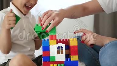 从梅卡诺的房子的特写。 一个女人和一个小男孩用彩色积木搭建一座房子，体验情感