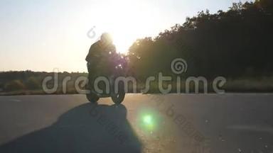 戴头盔的人骑着现代摩托车在高速公路上快速行驶，背景是太阳耀斑。 他的摩托车手