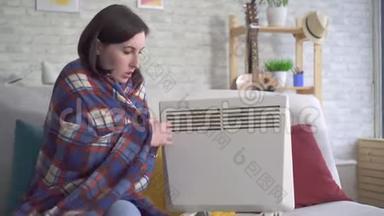 年轻女子在客厅里结冰，在<strong>电</strong>热器旁取暖