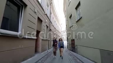 两个年轻的女人在维尔纽斯老城狭窄的街道<strong>上走来走去</strong>，谈笑风生。
