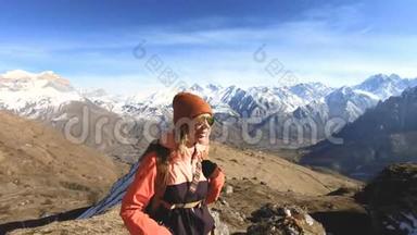 快乐的旅行者女孩摄影师戴着太阳镜，带着相机和背包，站在雪的背景上上坡