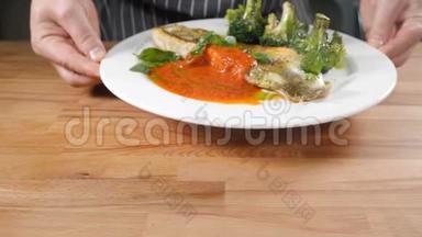 米其林星级餐厅美食概念.. 男厨师拿着盘子和鱼盘，配上绿色西兰花。 厨师服务