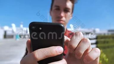 年轻人滚动智能手机屏幕。 商人用他的智能手机和滚动屏幕在城市的屋顶上