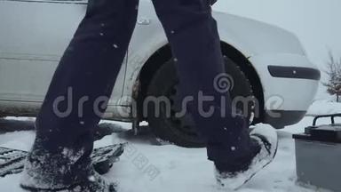 人类在冬天从积雪覆盖的地面上举起汽车电池，并把它带到汽车上。 一次修理或修理
