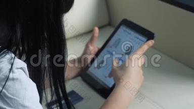 女孩用数字平板电脑制作<strong>网上</strong>购物概念。 黑发女人躺在沙发上看<strong>网上</strong>商店付钱
