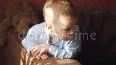 小男孩躺在沙发上环顾四周。 <strong>一缕</strong>阳光把婴儿照在沙发上。