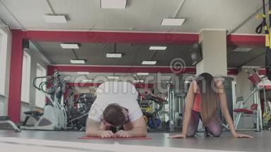 在健身房和女教练单独训练后，男人<strong>很累</strong>。 一个肥胖的男人和一个女教练