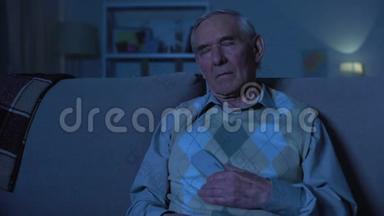 老人拿着遥控器睡在电视机前，晚上在家